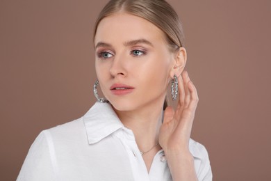 Photo of Beautiful young woman with elegant jewelry on light brown background