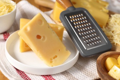 Photo of Grated, cut cheese and grater on table, closeup