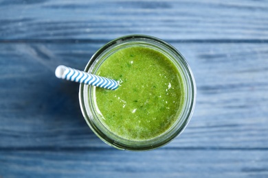 Delicious fresh green juice with straw on blue wooden table, top view