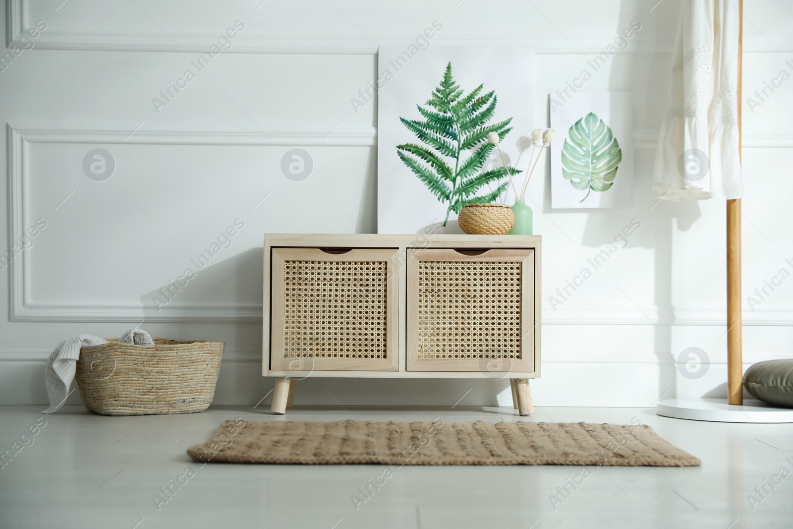 Photo of Wooden commode near white wall in room. Interior design