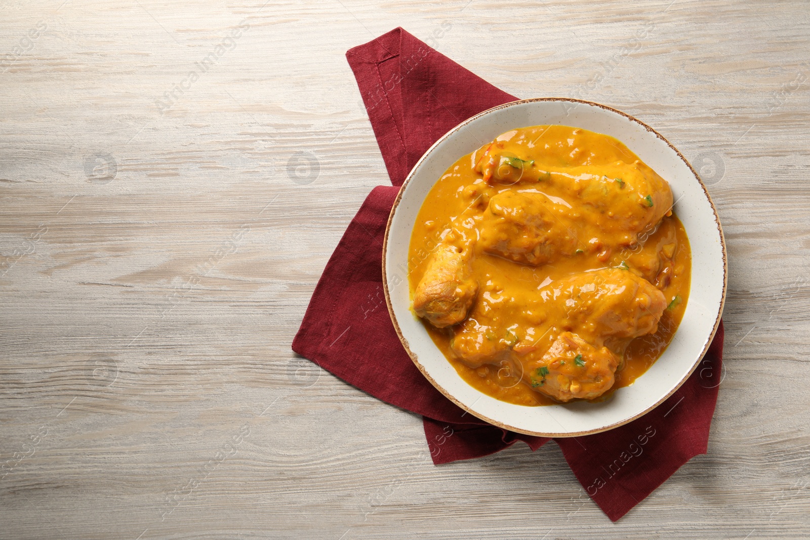 Photo of Tasty chicken curry on wooden table, top view. Space for text