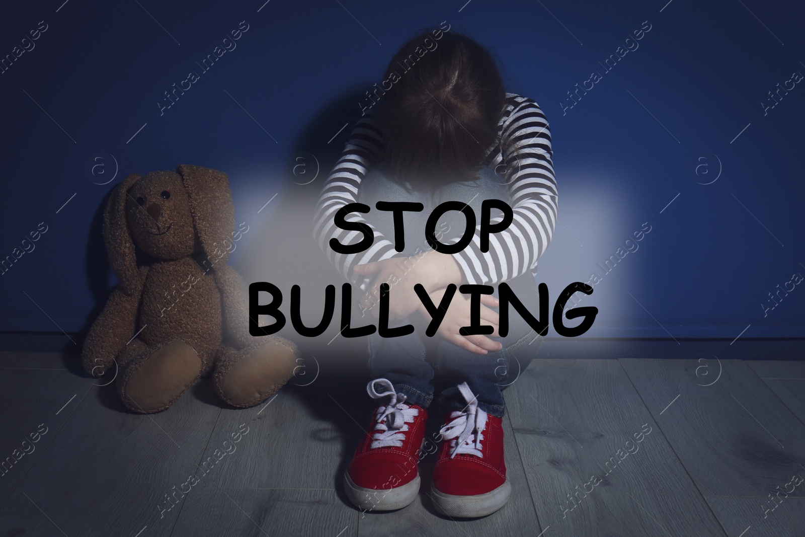 Image of Message STOP BULLYING and abused little girl crying near blue wall