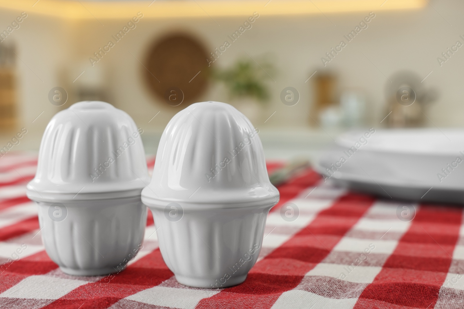 Photo of Ceramic salt and pepper shakers on kitchen table. Space for text