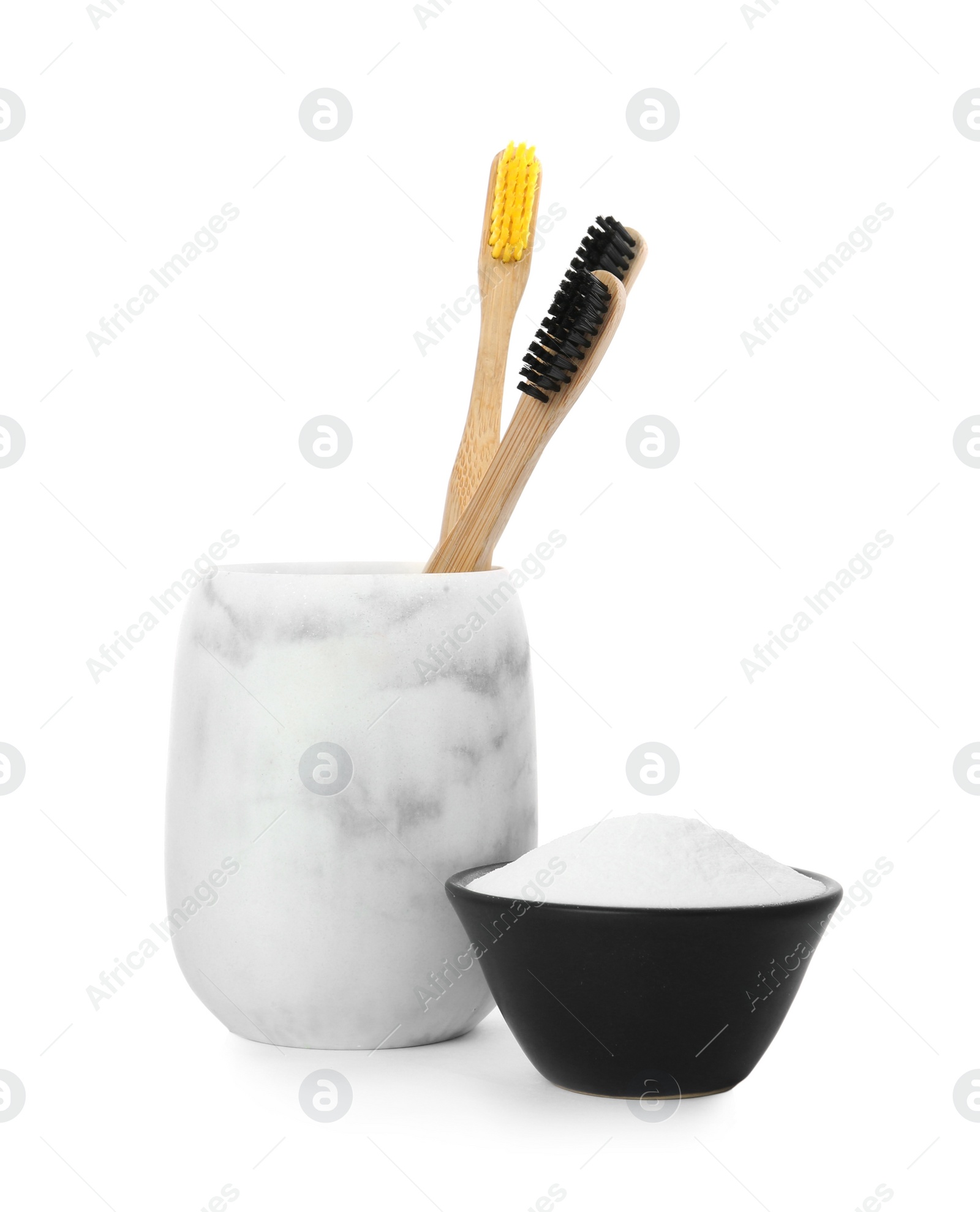 Photo of Bamboo toothbrushes in holder and bowl with baking soda on white background