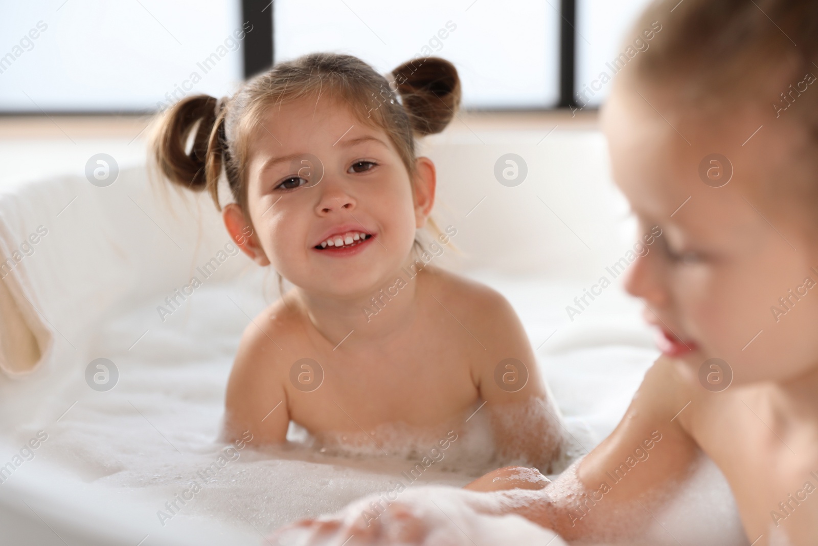 Photo of Cute little sisters taking bubble bath together