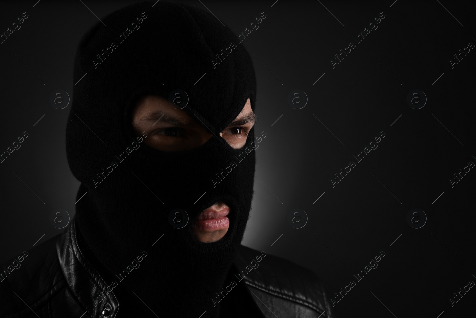 Photo of Man wearing knitted balaclava on black background, space for text