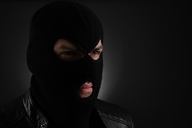 Man wearing knitted balaclava on black background, space for text