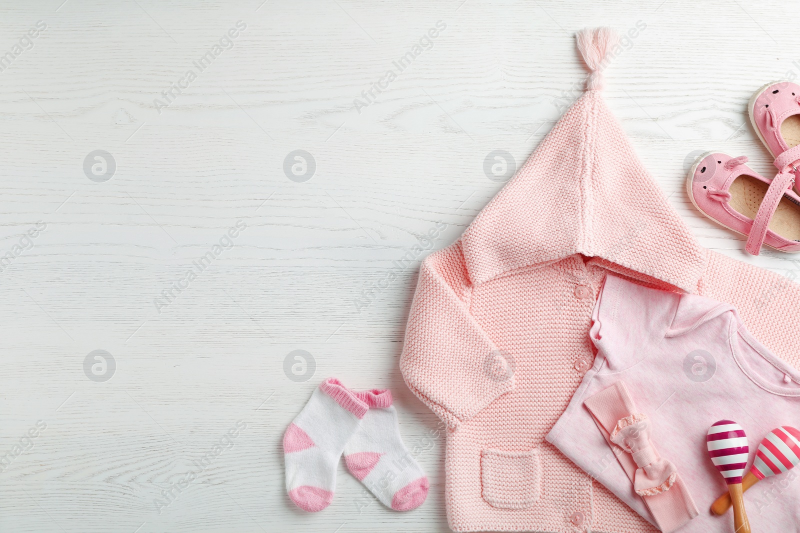 Photo of Flat lay composition with cute clothes and space for text on white wooden background. Baby accessories