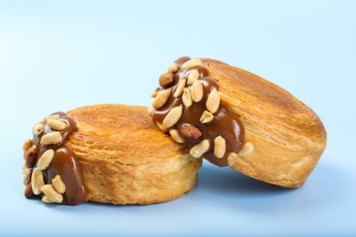 Supreme croissants with chocolate paste and nuts on light blue background, closeup. Tasty puff pastry