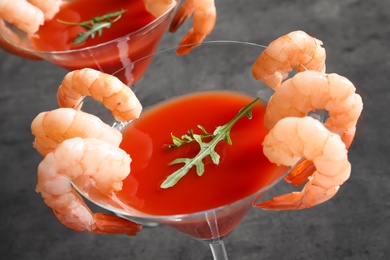 Glasses with boiled shrimps and tomato sauce on grey background