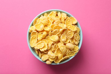 Bowl of tasty crispy corn flakes on pink background, top view