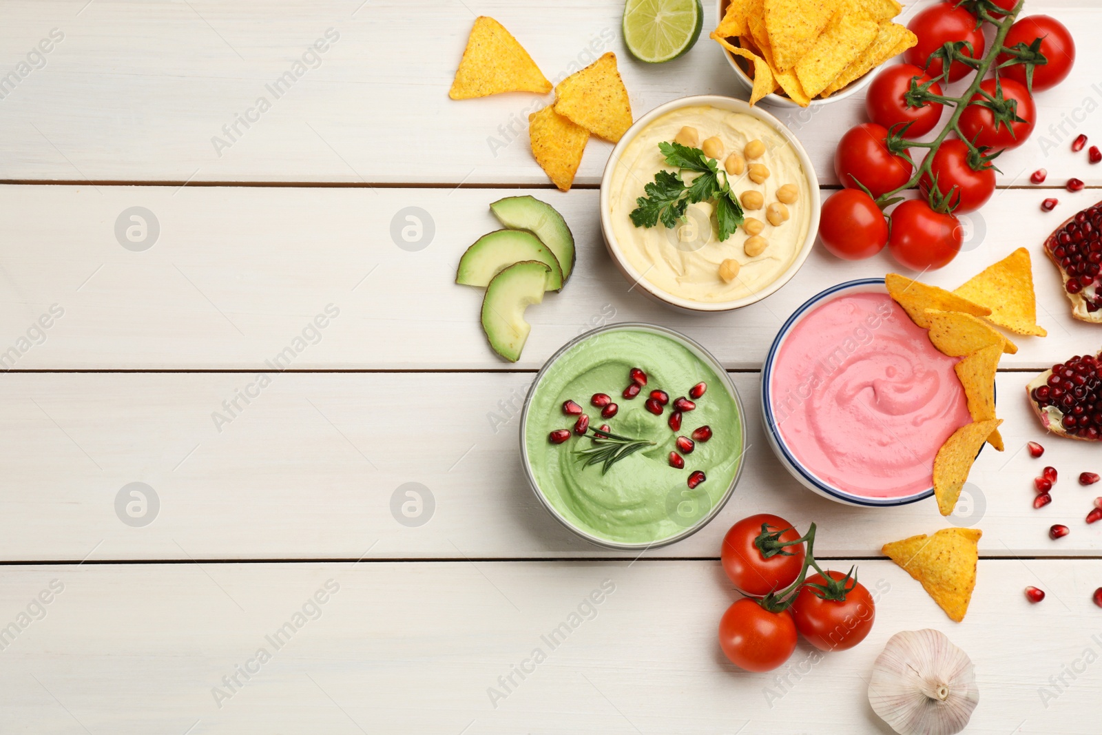 Photo of Flat lay composition with delicious hummuses on white wooden table. Space for text