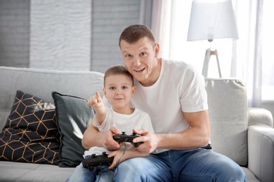 Photo of Happy dad and his son playing video games at home. Father's day celebration