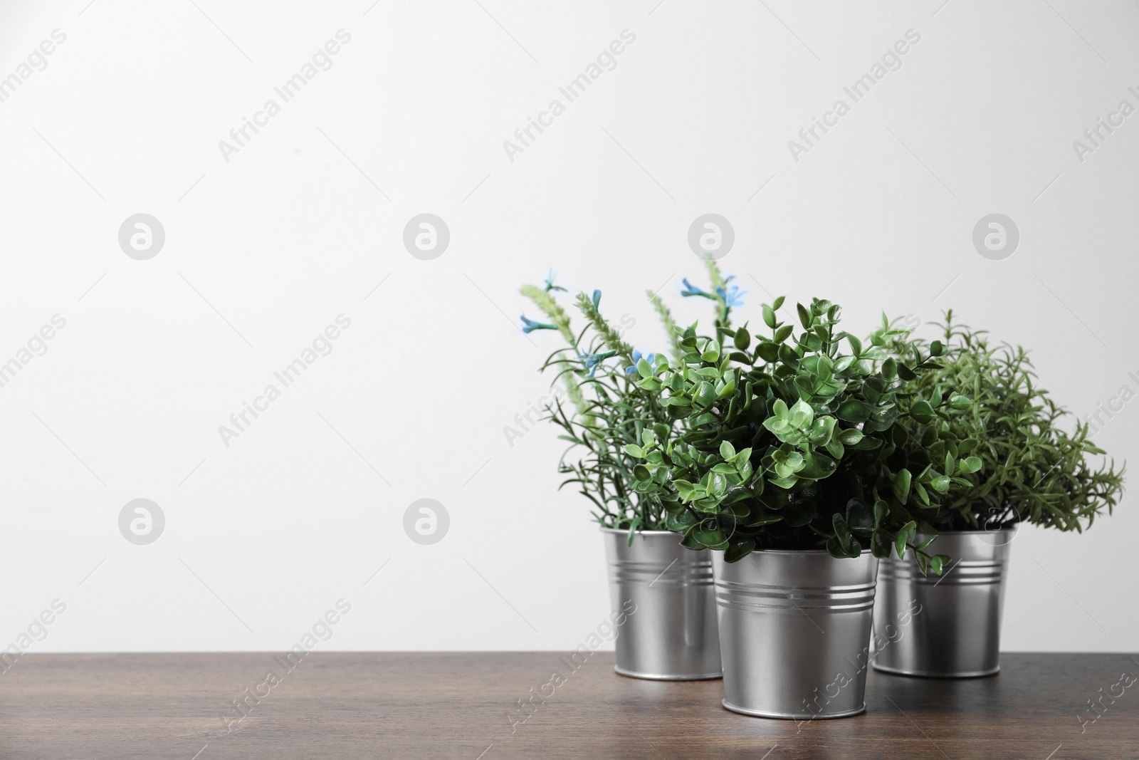 Photo of Different artificial potted herbs on wooden table against white background, space for text