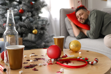 Photo of Man sleeping after New Year party, focus on messy table