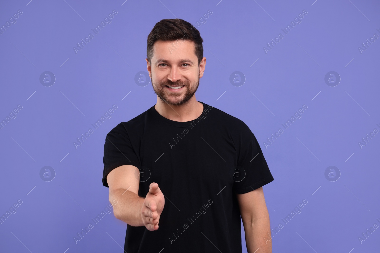 Photo of Happy man welcoming and offering handshake on purple background