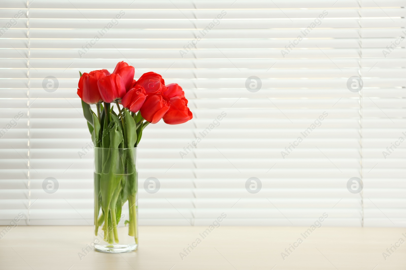 Photo of Window with blinds and beautiful bouquet on sill, space for text