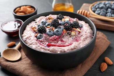 Photo of Tasty oatmeal porridge with toppings in bowl served on table, closeup