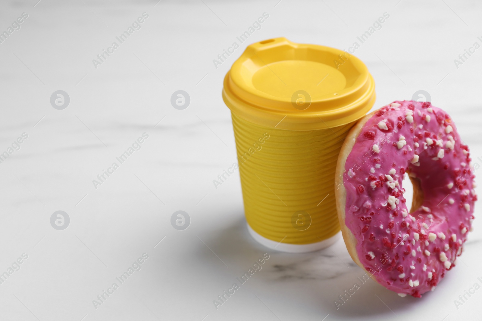 Photo of Tasty donut and cup of hot drink on white marble table, space for text