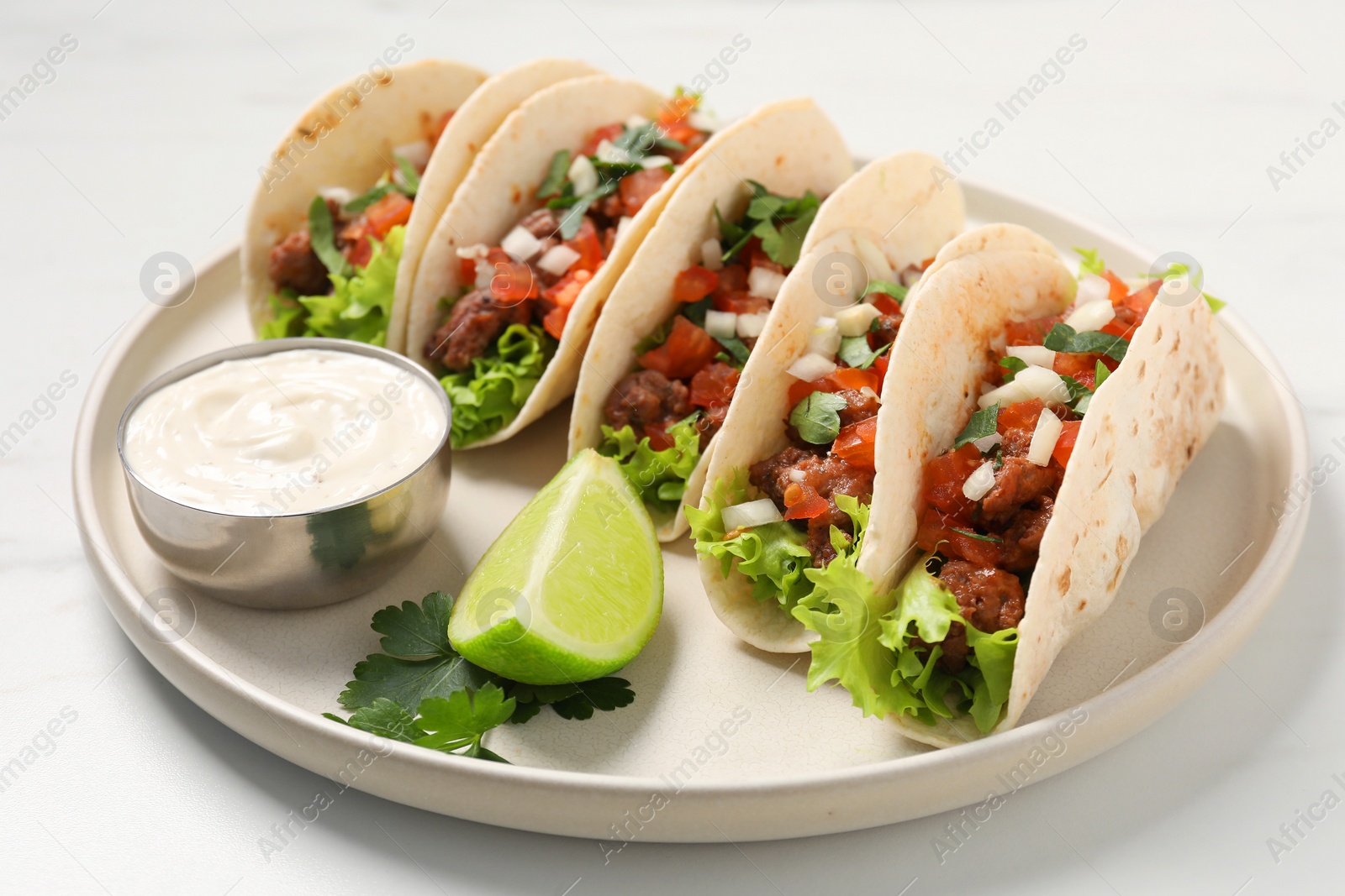 Photo of Delicious tacos with meat and vegetables served on light table, closeup