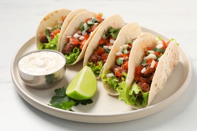 Photo of Delicious tacos with meat and vegetables served on light table, closeup