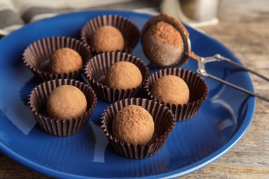 Plate with chocolate truffles on wooden background