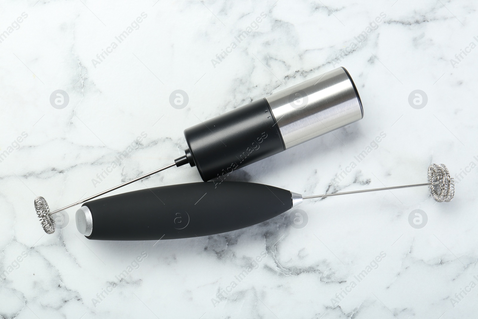 Photo of Black milk frother wands on white marble table, top view