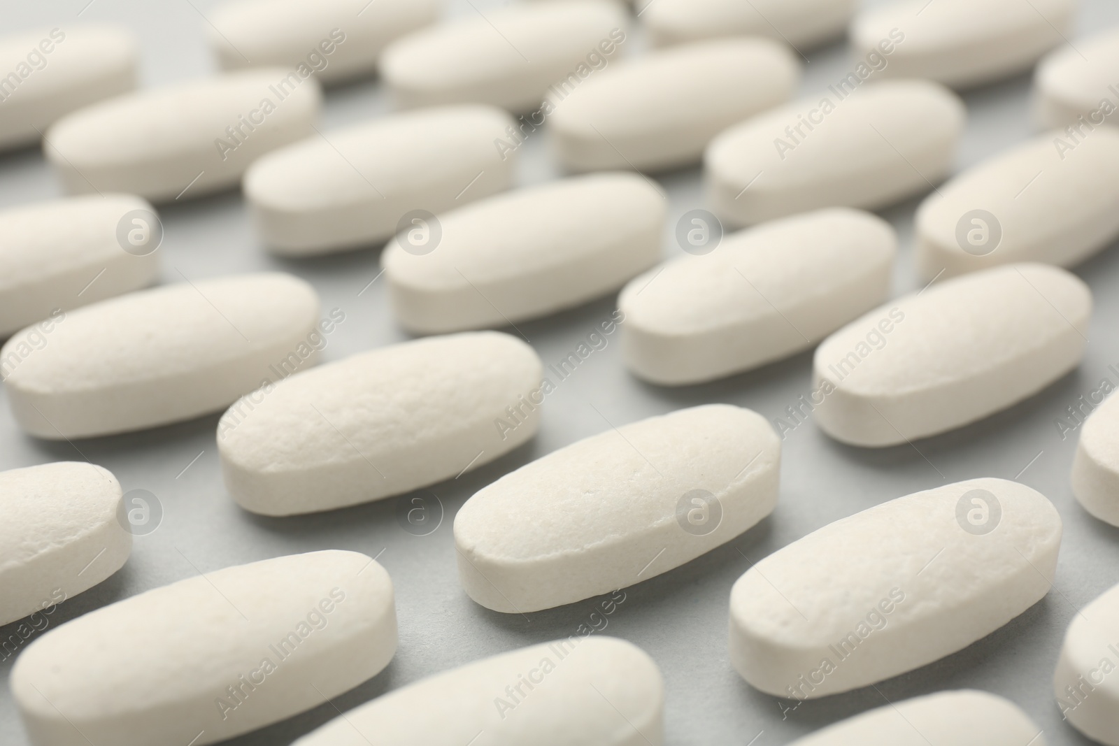 Photo of Vitamin pills on light grey background, closeup. Health supplement