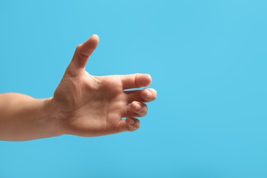 Photo of Woman holding something in hand on light blue background, closeup. Space for text