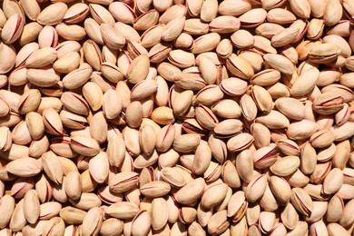 Photo of Many tasty pistachios as background, top view