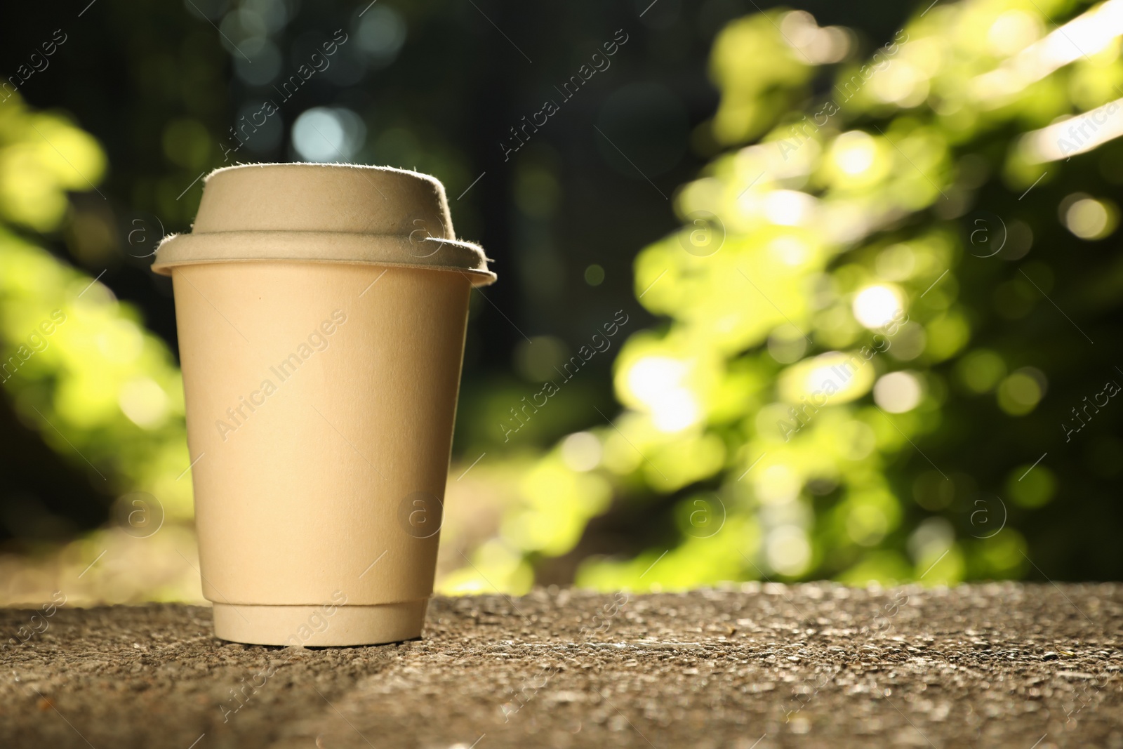 Photo of Cardboard takeaway coffee cup with lid on stone parapet outdoors, space for text