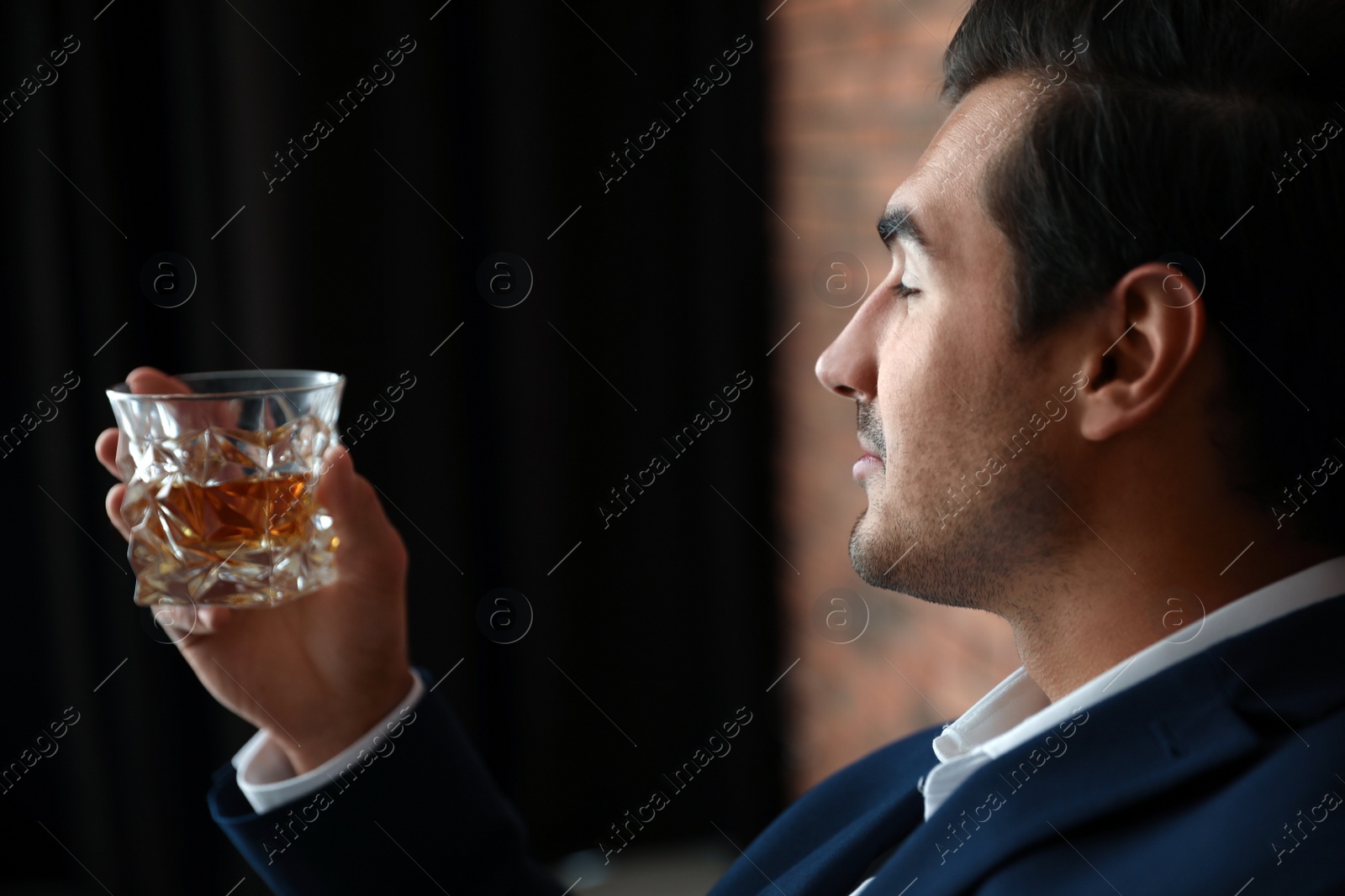 Photo of Young man with glass of whiskey indoors