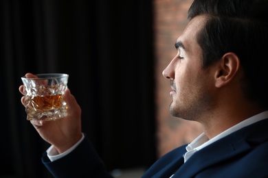 Photo of Young man with glass of whiskey indoors