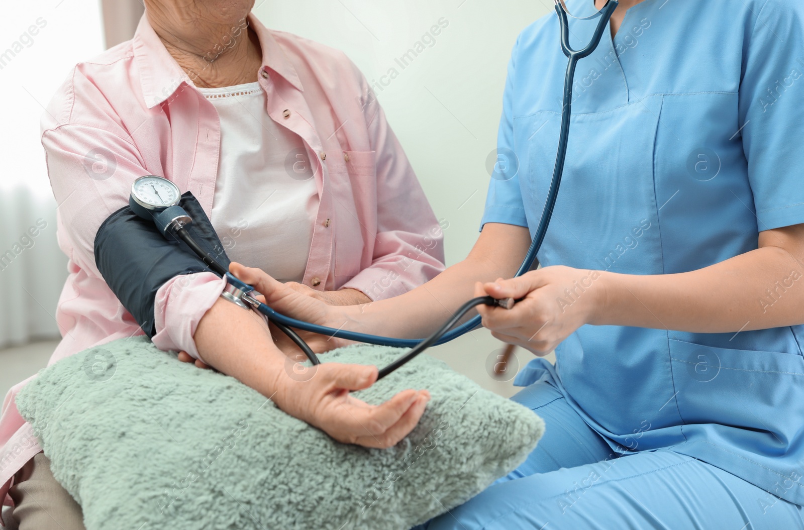 Photo of Nurse measuring blood pressure of elderly woman indoors, closeup. Assisting senior people
