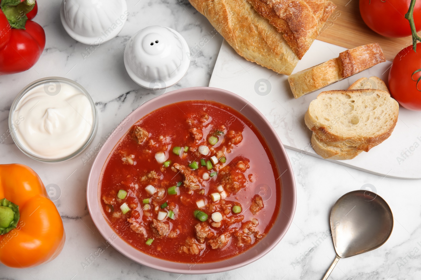 Photo of Bowl of delicious stuffed pepper soup served on white marble table, flat lay