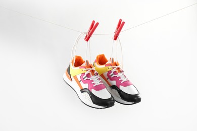 Photo of Stylish sneakers drying on washing line against light grey background