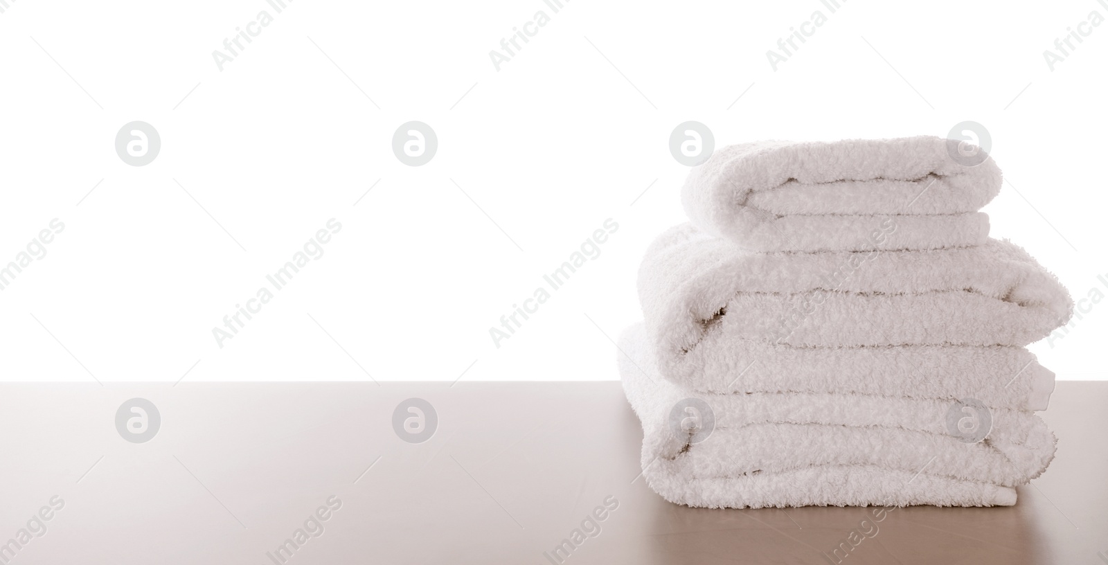 Photo of Fresh towels on light grey table against white background. Space for text