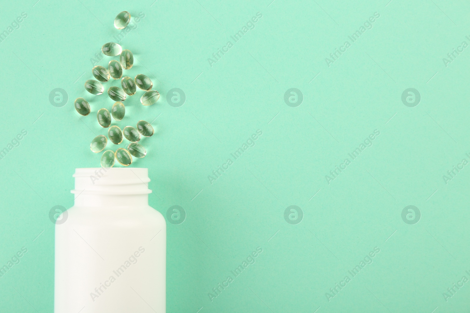 Photo of Bottle and vitamin capsules on turquoise background, top view. Space for text