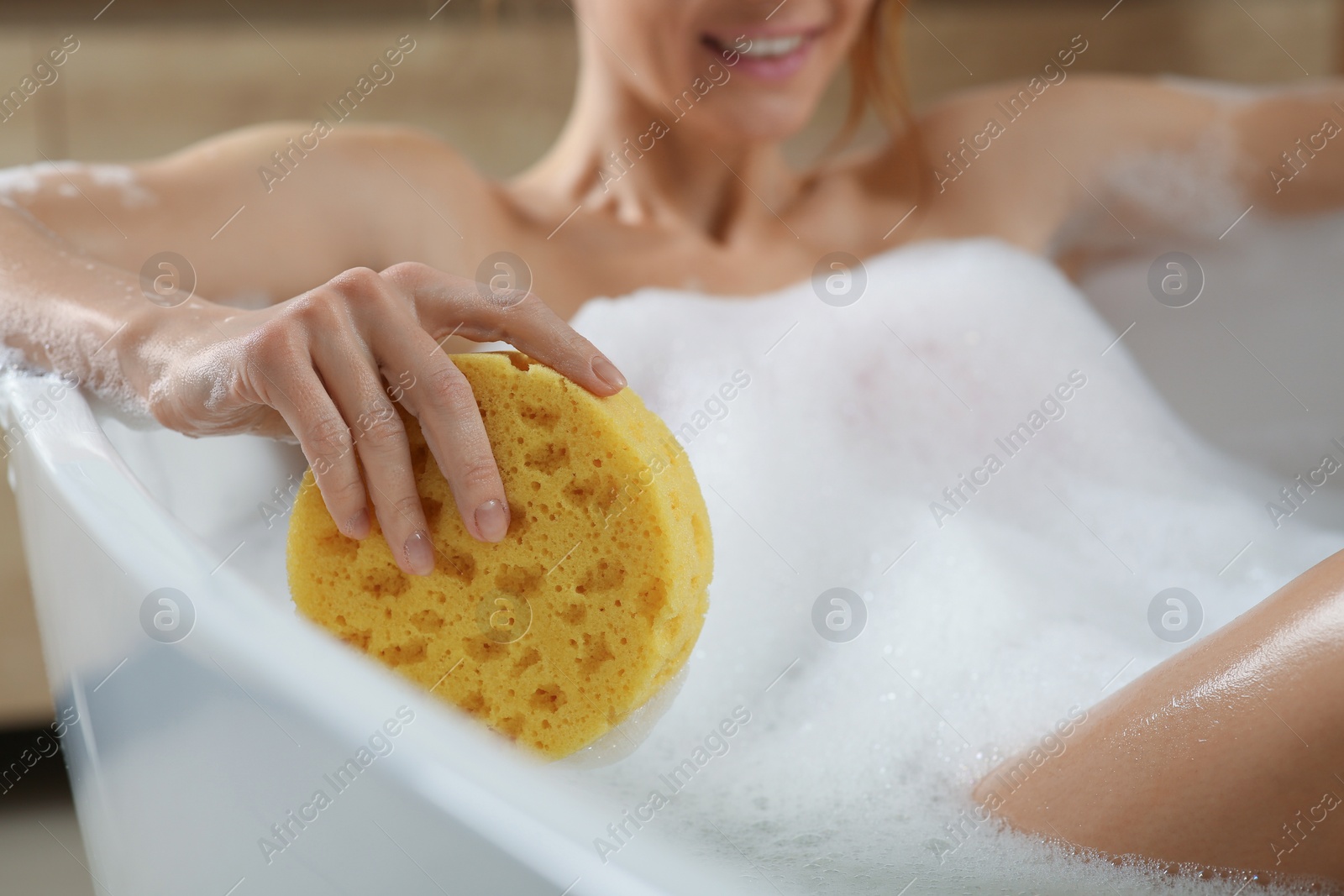 Photo of Woman with sponge taking bubble bath, closeup