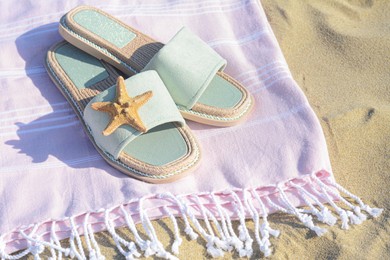 Photo of Pink blanket with stylish slippers and dry starfish on sandy beach, closeup