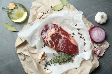 Piece of raw beef meat and spices on grey table, flat lay