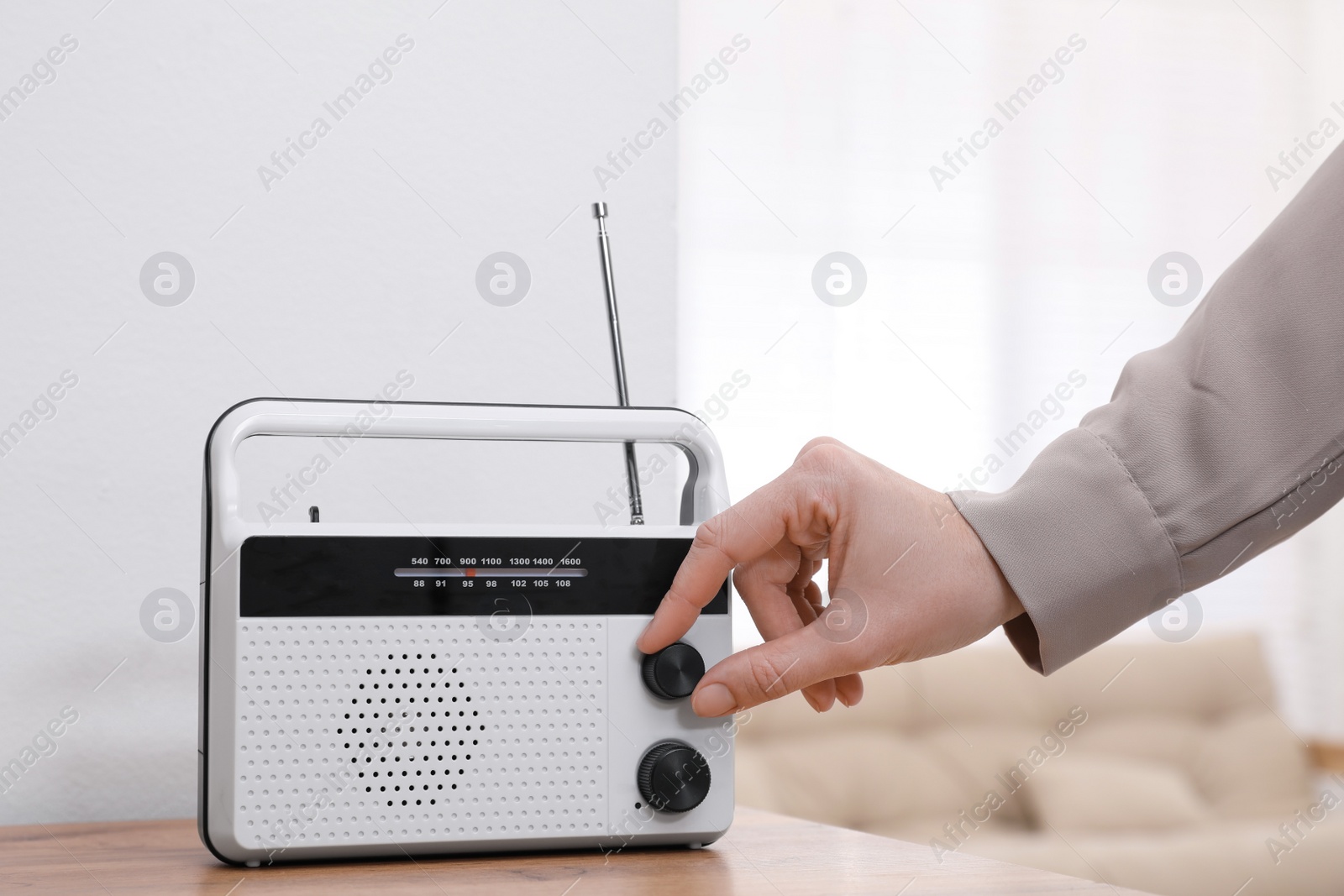 Photo of Woman turning volume knob on radio at home, closeup