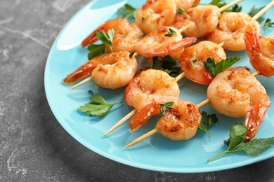 Plate with delicious fried shrimp skewers on grey background, closeup