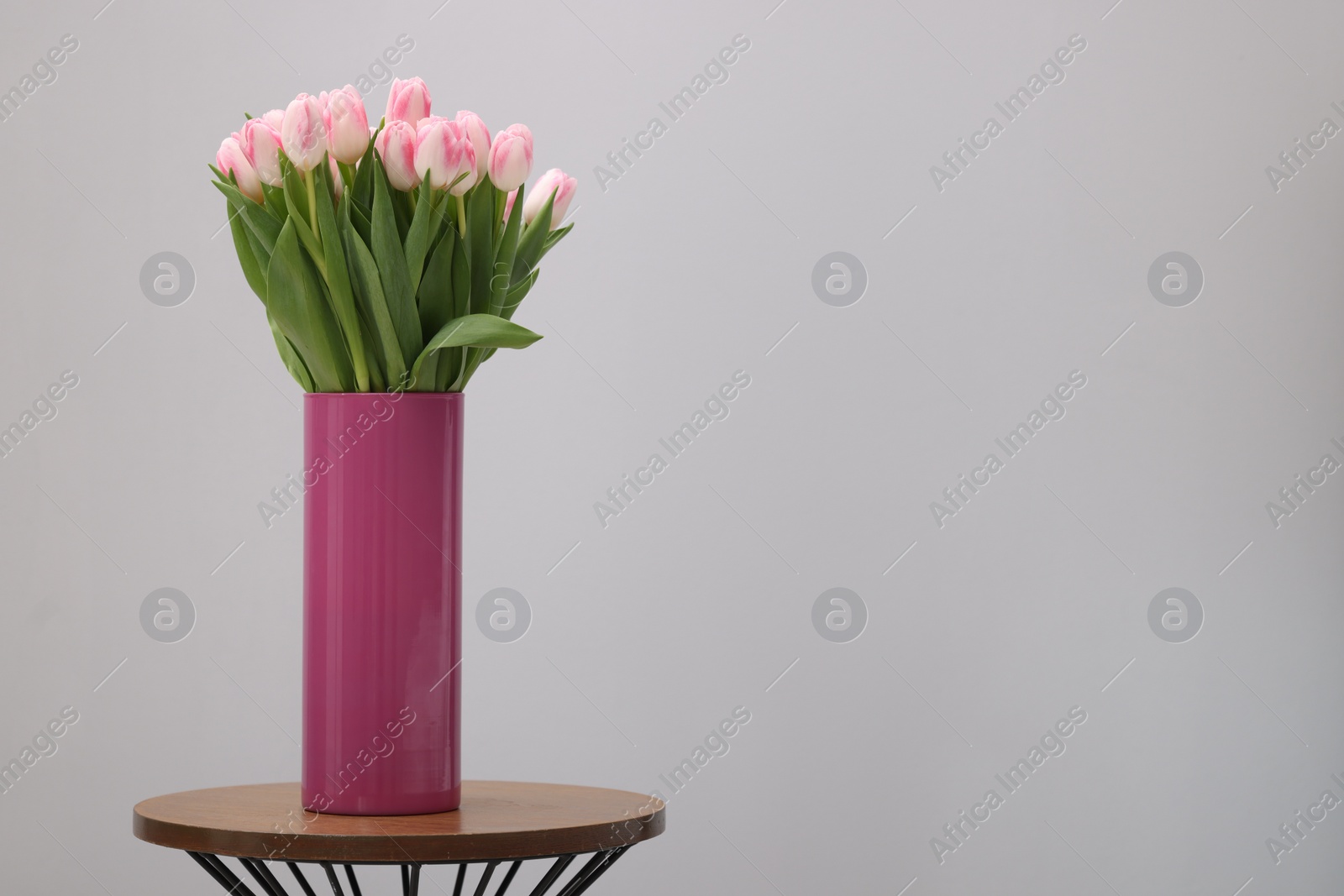 Photo of Beautiful bouquet of fresh pink tulips on table against light grey background. Space for text