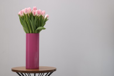 Beautiful bouquet of fresh pink tulips on table against light grey background. Space for text