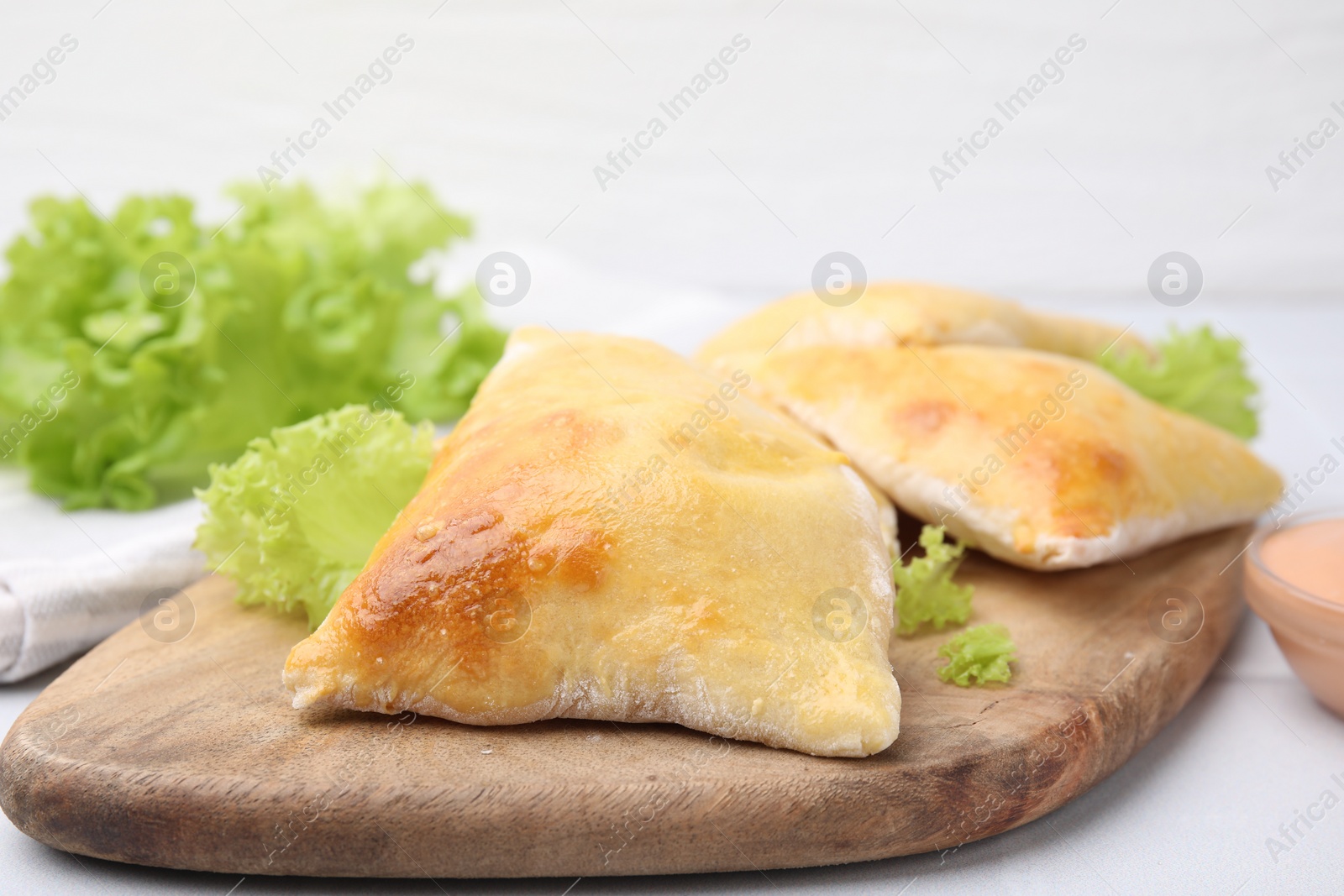 Photo of Delicious samosas and lettuce on white table, closeup