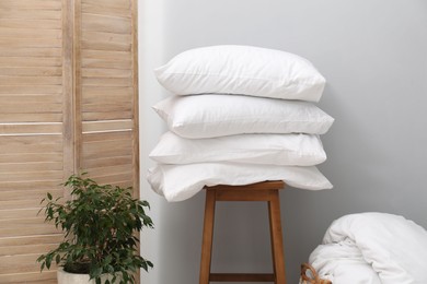 Photo of Soft pillows, duvet, chair and houseplant indoors