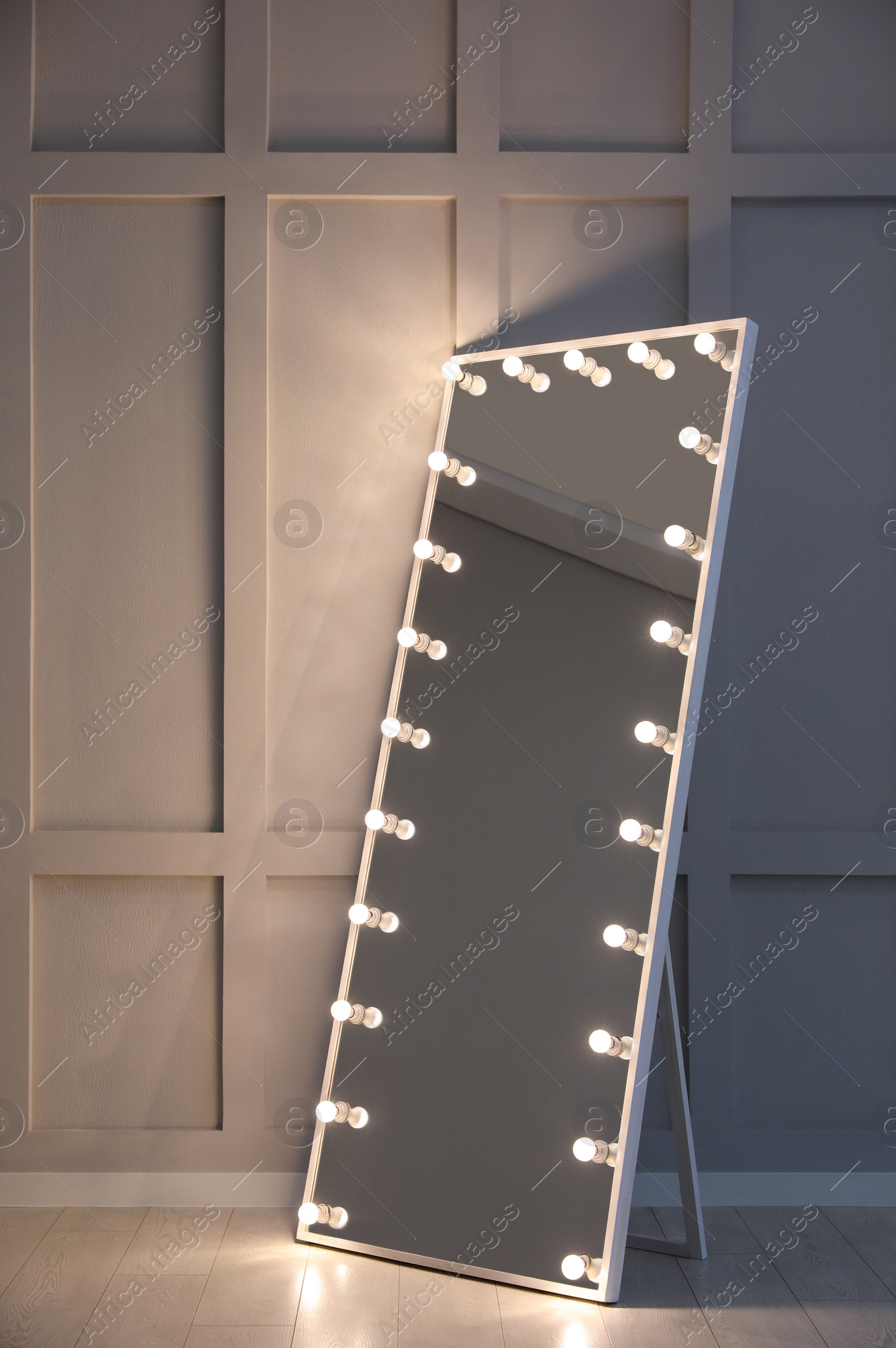 Photo of Modern mirror with light bulbs near molding wall in room