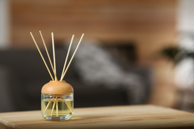 Photo of Aromatic reed air freshener on table indoors. Space for text