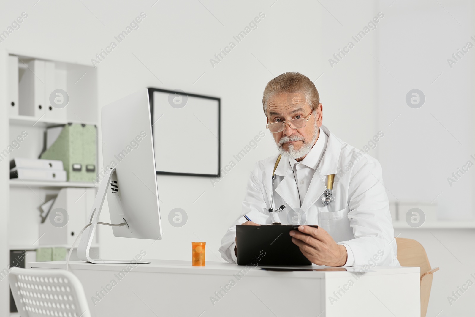 Photo of Doctor with patient's medical card at table in clinic